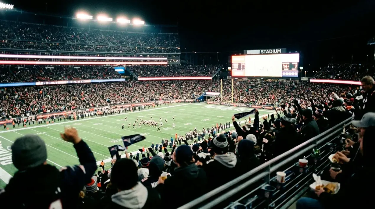 Stopwatch over a stadium scoreboard at night with primetime broadcast logos and prop tickets